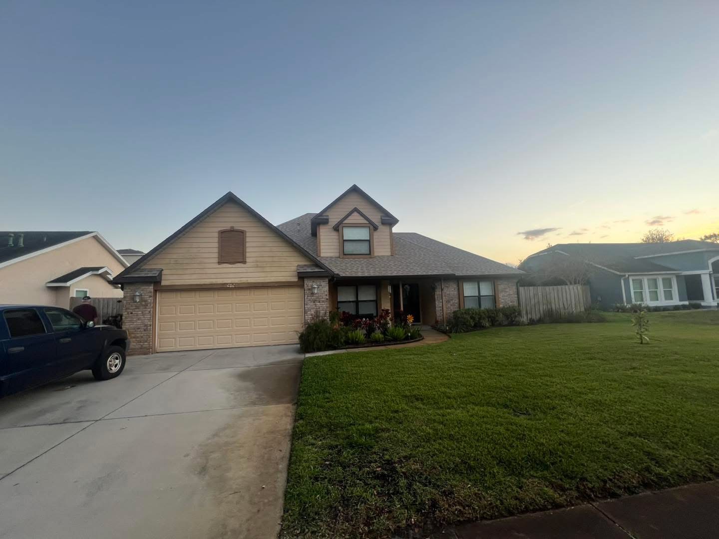 Two-story home with faded tan siding before exterior repaint